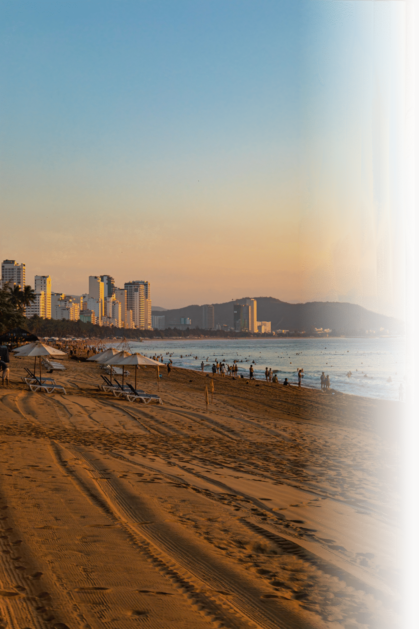 Praia movimentada raia ao entardecer com pessoas aproveitando o mar, simbolizando lazer e bem-estar promovidos pela Nova Aparelhos Auditivos.