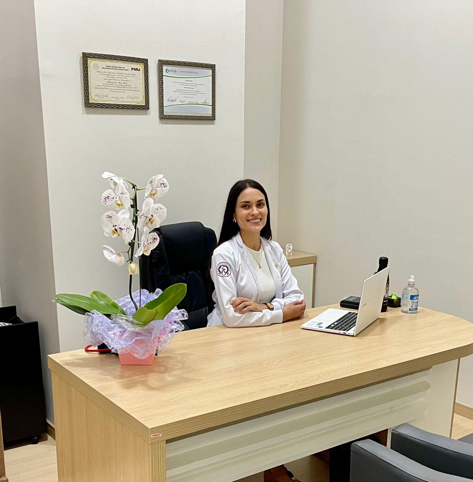 Fonoaudióloga Mariana Costa, sentada em sua mesa.